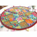 Stunning Barmer green round table runner close-up displaying handcrafted cotton embroidered patchwork with floral and leaf designs, tassels, and textured details