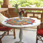 Stunning Barmer green round table runner close-up displaying handcrafted cotton embroidered patchwork with floral and leaf designs, tassels, and textured details
