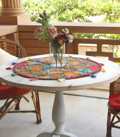 Stunning Barmer green round table runner close-up displaying handcrafted cotton embroidered patchwork with floral and leaf designs, tassels, and textured details