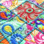 Stunning Barmer green round table runner close-up displaying handcrafted cotton embroidered patchwork with floral and leaf designs, tassels, and textured details